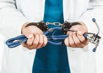 Close-up Of Doctor Hands With Stethoscope In Handcuffs.