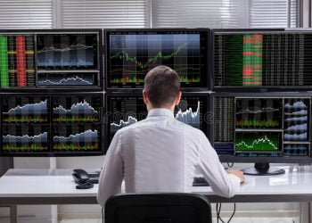stock-market-broker-analyzing-graphs-computer-screens-side-view-young-male-multiple-126320282
