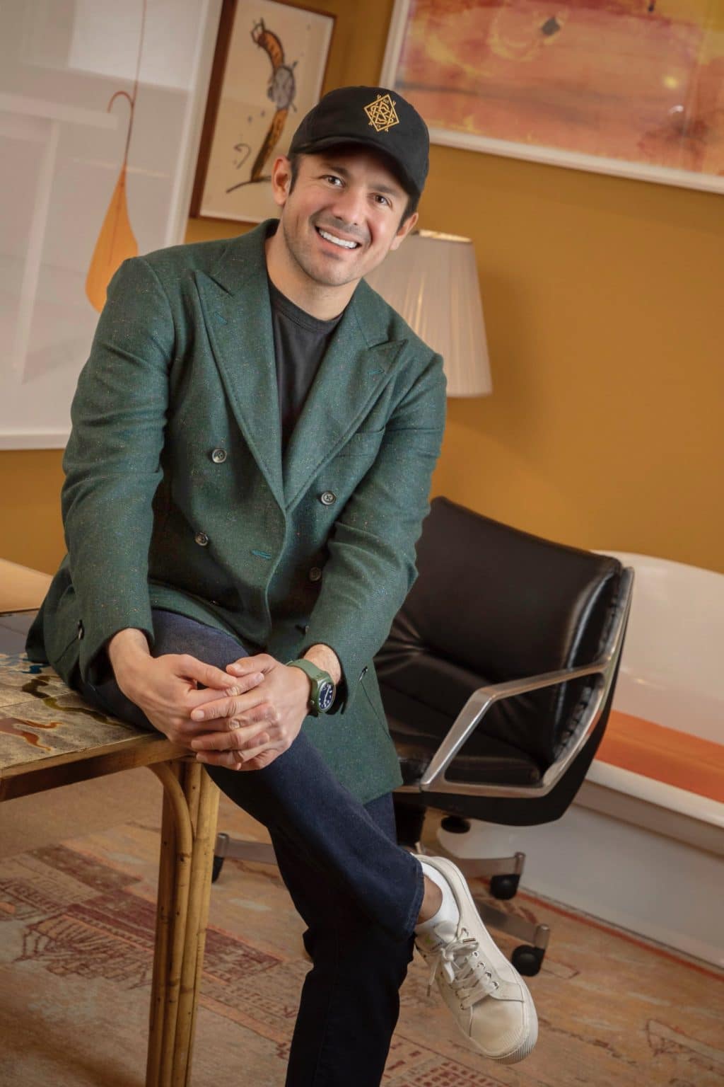 Phillip Sarofim in a green blazer leaning on a bamboo table inside an yellow colored office