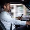 A middle aged caucasian man distracted driving while using a mobile device stops his vehicle suddenly to avoid an accident.