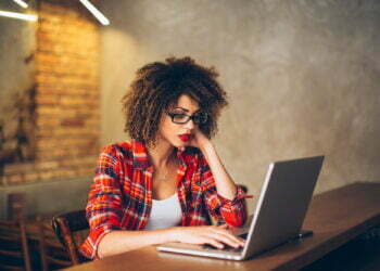 Young woman sitting at cafe working on laptop