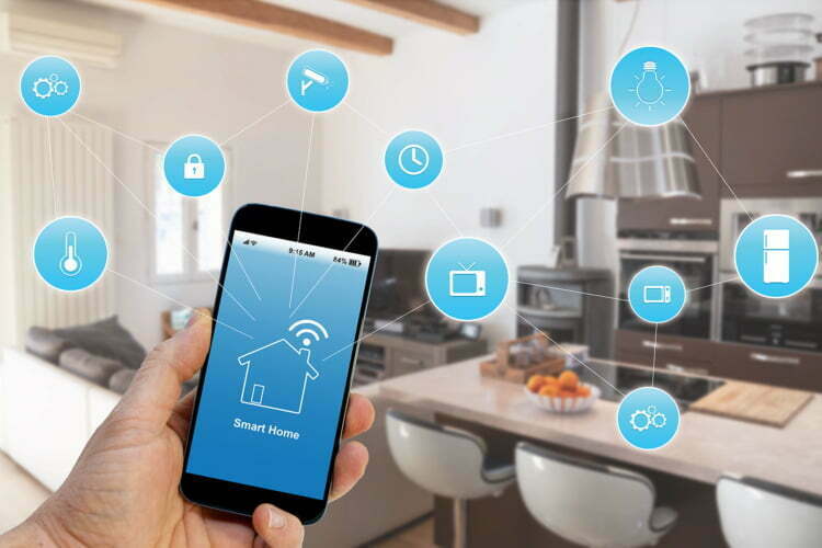 Hand holding smartphone with smart home application on screen
