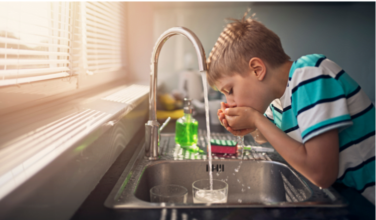 a boy drinking water from the tap