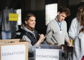Volunteers at a charity event, organizing and collecting donations, embodying the philanthropic spirit inspired by advocates like Janine Lowy.