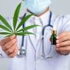 medical doctor holding cannabis leaf bottle cannabis oil white wall 1150 26701