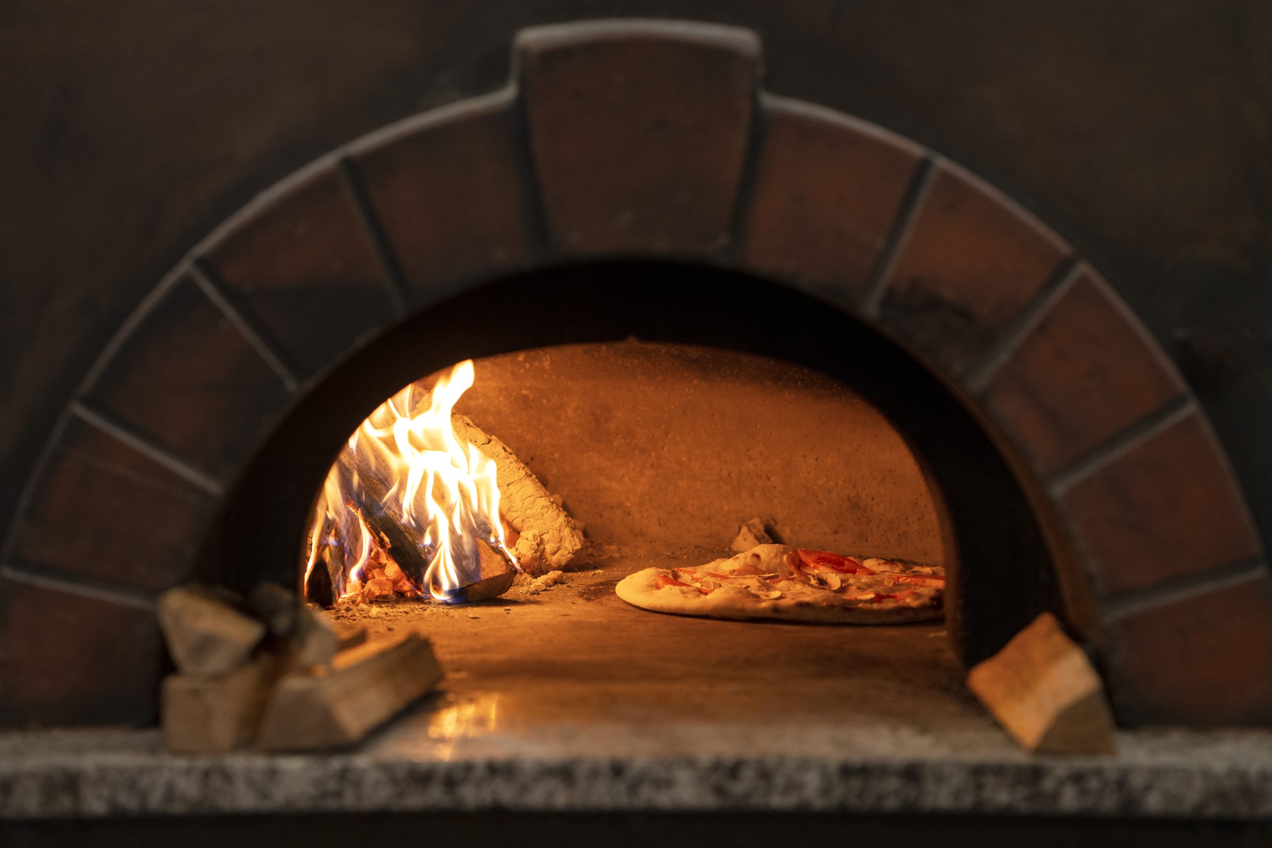 baking delicious pizza with wood fired oven scaled