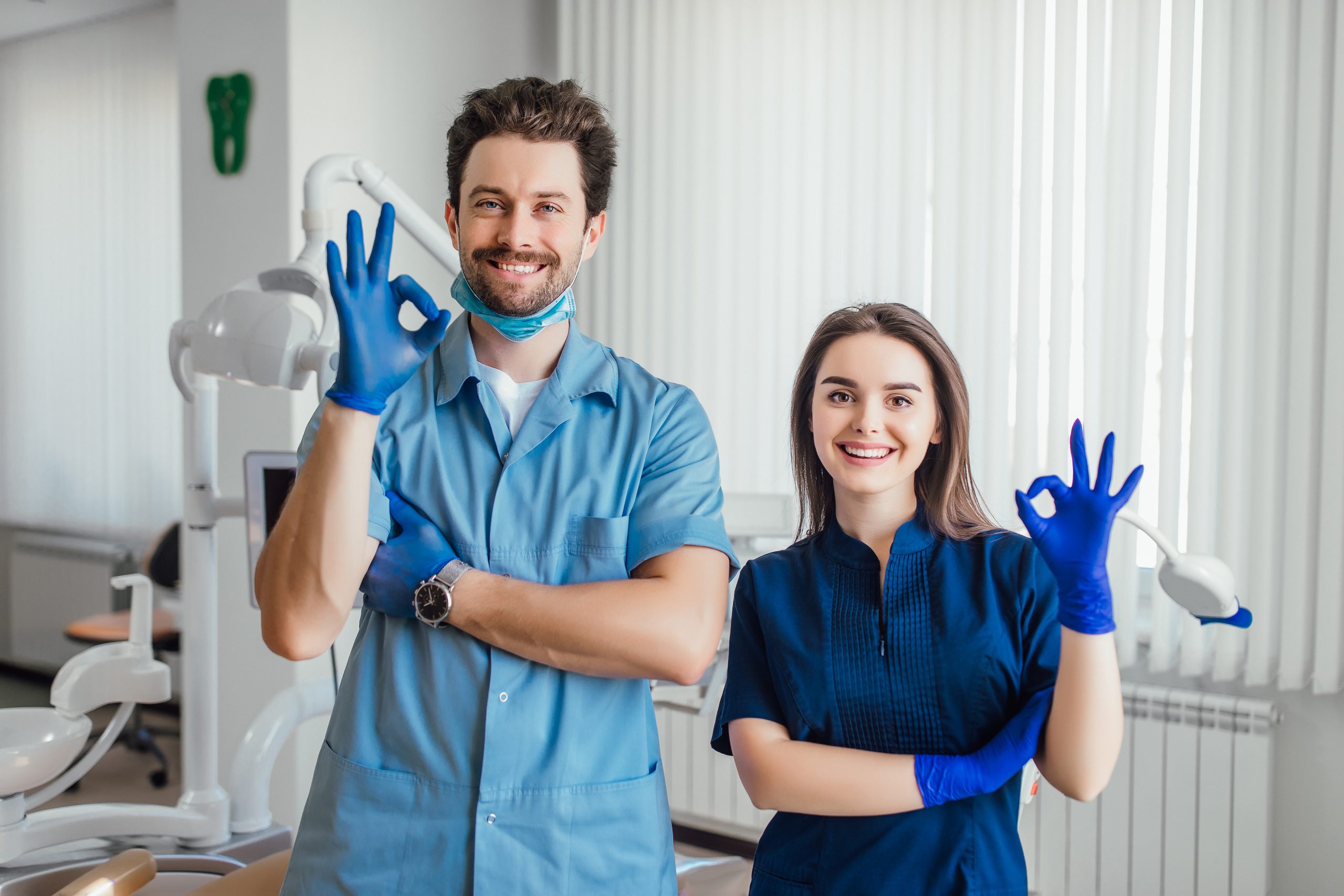 photo smiling dentist standing with arms crossed with her colleague showing okay sign scaled