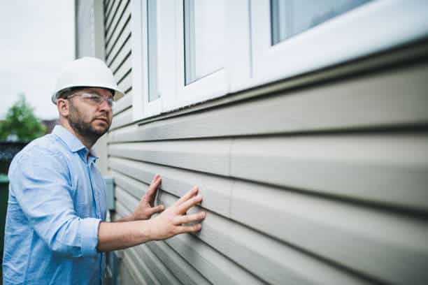 Building inspector at work. He is inspecting the windows of a residential building.