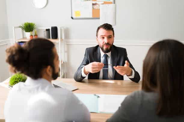 Hispanic divorce attorney explaining the legal procedure to a couple signing the papers