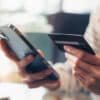 Woman hand holding credit cards and using smartphone for shopping online with payment on internet banking.