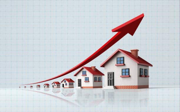 High quality 3d render of miniature houses on a blue graph paper. Housing market concept. Miniature houses are lit by the upper left corner of composition. A red arrow in the composition is symbolizing a sharp increase in sales. Vertical composition with copy space. Great use for real estate and morgage related concepts.