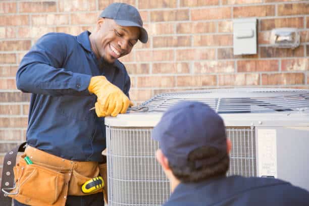 Multi-ethnic team of blue collar air conditioner repairmen at work. They prepare to begin work by gathering appropriate tools from their tool box.