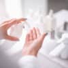 Close up female hands holding bottle of soap opposite sink. Skin care treatment concept