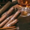 Cigars, luxury smoking concept. Cuban cigars in a wooden box, blur glass of cognac brandy, closeup view with details, copy space