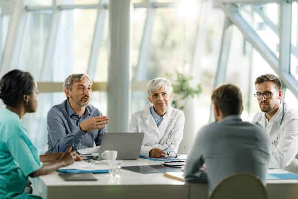 Team of doctors and businessmen communicating while having a meeting at doctor's office in the hospital.