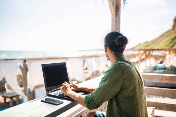 Young businessman is working on the beach and enjoying his day.