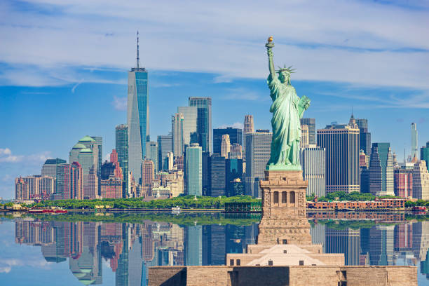 Statue of Liberty and New York City Skyline with Manhattan Financial District, Battery Park, Water of New York Harbor, World Trade Center, Empire State Building, Governors island and Blue Sky with Puffy Clouds. HDR image. Canon EOS 6D (full frame sensor) camera. Canon EF 70-200mm f/4L IS USM Lens.