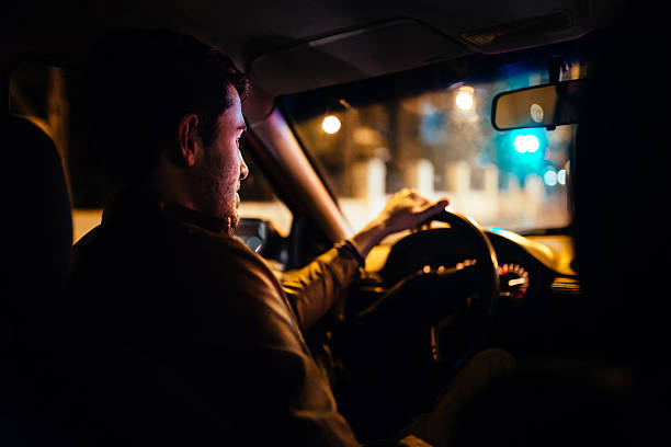 Interior view of a man driving his private taxi through the city streets at night