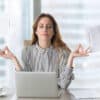 Calm female executive meditating taking break at work for mental balance, mindful businesswoman feeling relief and no stress doing yoga at work ignoring avoiding stressful job and paperwork in office
