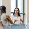 The young adult woman gestures as she details her experience during the interview with the unrecognizable businesswoman.