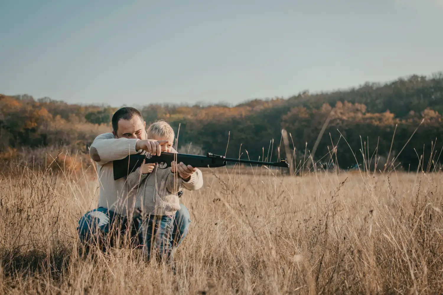 Father's day. Father with gun showing something to son while hunting on a nature. Happy family